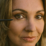 Close-up of a woman's face with a makeup brush near her eye.