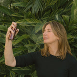 Woman holding a bottle against a green leafy background