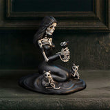Skeletal mermaid figurine with three skeleton cats on a dark background