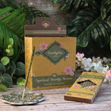 Eucalyptus spiritual smudge incense packaging with floral design on a wooden surface with greenery in the background.