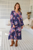 Woman wearing a floral dress in a bright, sunlit room.