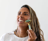 Woman using a facial roller on her face against a white background