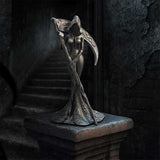 Statue of a woman with a hooded cloak and a scythe on a dark background