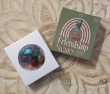 Box of friendship stones with a card on a textured surface
