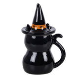 Black ceramic mug shaped like a witch's boot with a hat on a white background