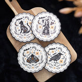 Four decorative coasters with animal illustrations on a wooden board against a dark background.