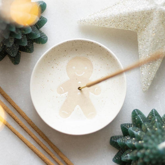 Gingerbread man soap on a white speckled plate with decorative elements on a light background