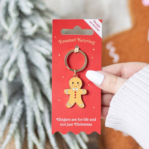 Gingerbread man keychain on a red card held by a hand with a blurred background