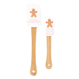 Two wooden spoons with gingerbread man designs on white cards on a white background