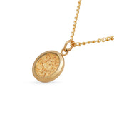 Gold necklace with a round pendant on a white background
