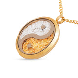 Gold necklace with a yin yang pendant on a white background