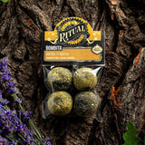 Packaged product labeled 'Ritual Bombita' on a tree trunk with lavender flowers.