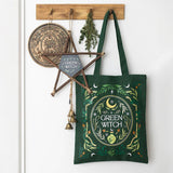 Green witch-themed tote bag hanging on a hook with decorative items.