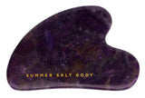 Purple gua sha tool with 'Summer Salt Body' text on a white background