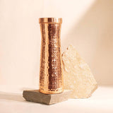 Copper water bottle with a textured design on a light background