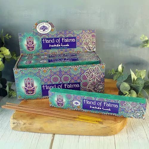 Box of 'Hand of Falima' incense sticks with packaging on a wooden board.