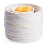 White ceramic container with wavy texture holding yellow wax cubes on a white background