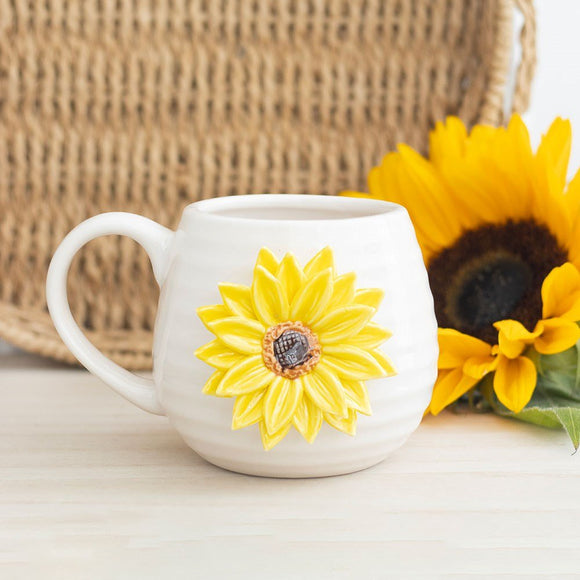 White mug with a yellow sunflower design on a light surface with a woven basket in the background.