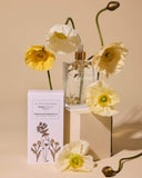 Bottle of perfume with a box labeled 'BOHO WOMEN' and yellow flowers on a beige background