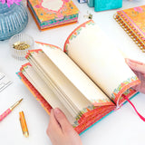 Colorful notebook with decorative edges on a desk with stationery items.