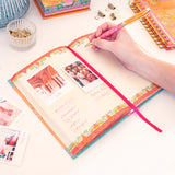 Person using a colorful planner with photos and notes on a white surface