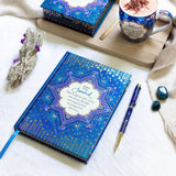 Blue journal with star design, mug, and pen on a white surface