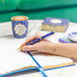 Person holding a pen over an open notebook with a blurred background