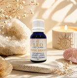 A bottle of Leo essential oil by Seaside Aromas sits on a stone slab in a styled setting with crystals, dried flowers, and a lit candle.