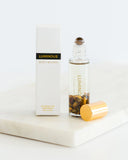 Luminous roller bottle with gold cap and packaging on a white surface
