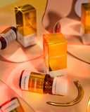 Luminous skincare products with gold packaging on a reflective surface