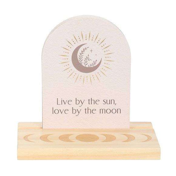 Decorative item with a moon and sun design and text 'Live by the sun, love by the moon' on a white background.