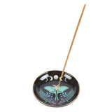 Incense holder with incense stick featuring a design of a moth and moon phases on a white background