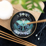 Decorative dish with butterfly design on a wooden surface with incense sticks.