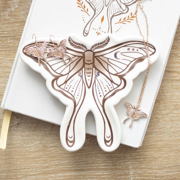 Butterfly-shaped jewelry dish with a necklace on a wooden surface