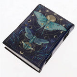 A small hardcover notebook or journal with a dark navy blue cover decorated with metallic gold geometric designs, moons, and two large metallic blue-green butterflies, shown on a plain white background.