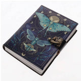 A hardcover journal with a dark blue cover featuring detailed illustrations of a blue butterfly, a dragonfly, and celestial designs, secured with a black strap and antique bronze clasp.