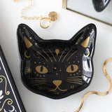 Black cat-shaped dish with gold detailing on a white surface