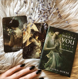 Three tarot cards on a textured surface with a hand and dried lavender.