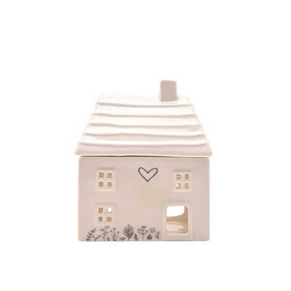 Ceramic house-shaped lantern with a heart design on a white background