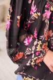 Close-up of a black floral dress with colorful flowers on a blurred background
