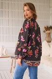 Woman wearing a black floral blouse in a home setting