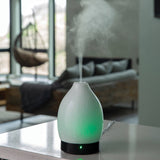 Diffuser emitting mist on a table with a blurred living room background
