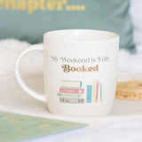 White mug with 'My Weekend is Fully Booked' text and book illustrations on a light background
