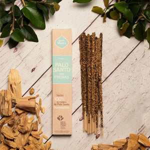 Palo Santo sticks with packaging on a wooden surface with green leaves.