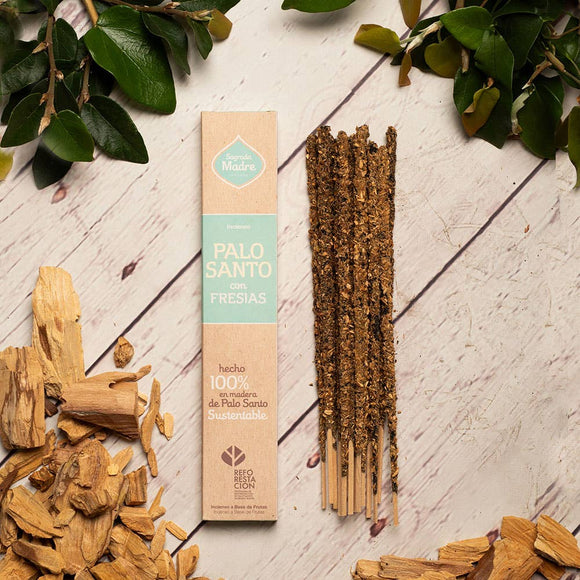 Palo Santo sticks with packaging on a wooden surface with green leaves.