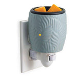 Wall-mounted wax warmer with a decorative container on a white background