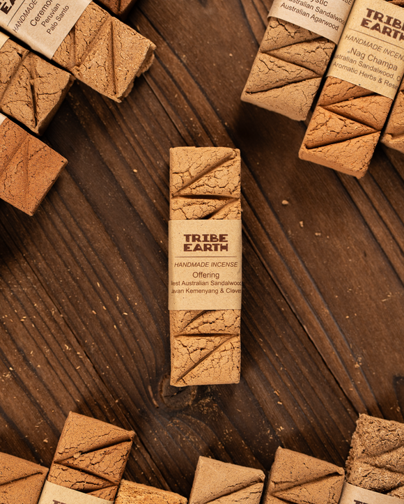 Tribe Earth handmade incense stick packaging on a wooden surface with other incense sticks.