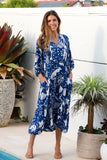 Woman wearing a blue patterned dress standing by a pool with plants around.