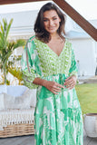 Woman wearing a green and white patterned dress outdoors.
