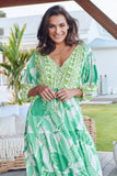 Woman wearing a green and white patterned dress outdoors.